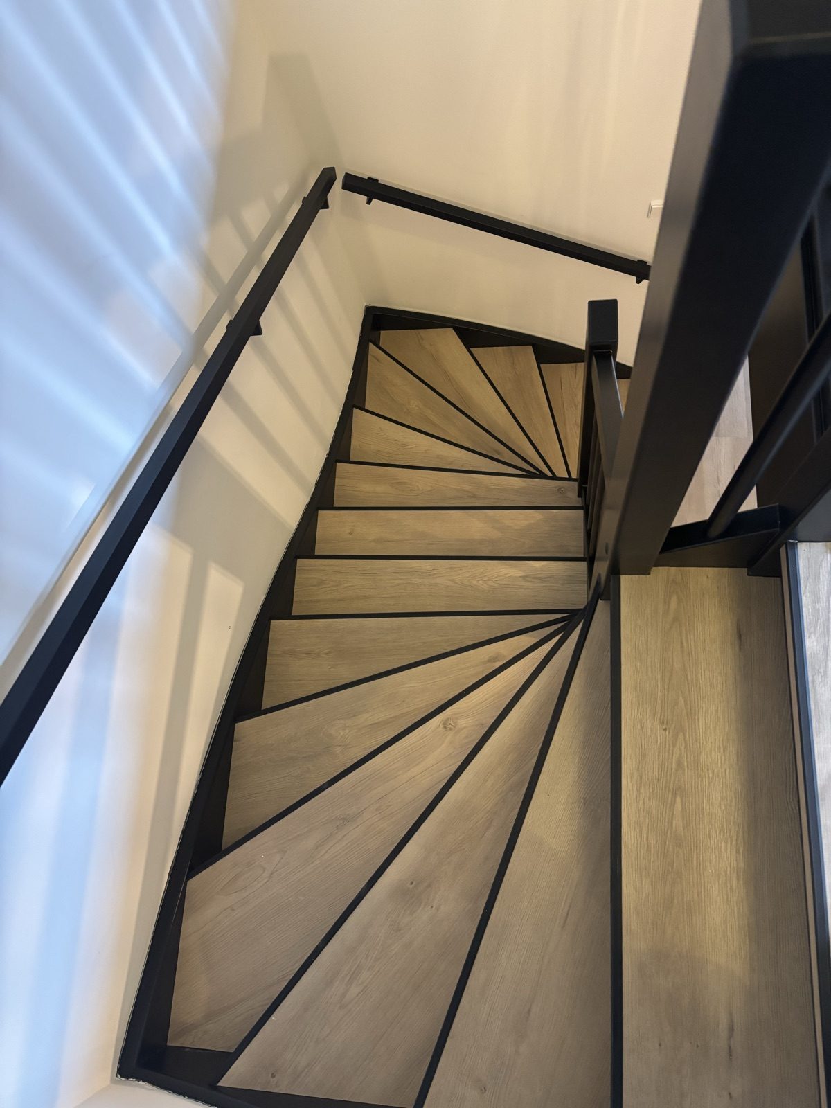 Gerenoveerde trap met houtlook PVC treden en zwart staal Den Haag - na